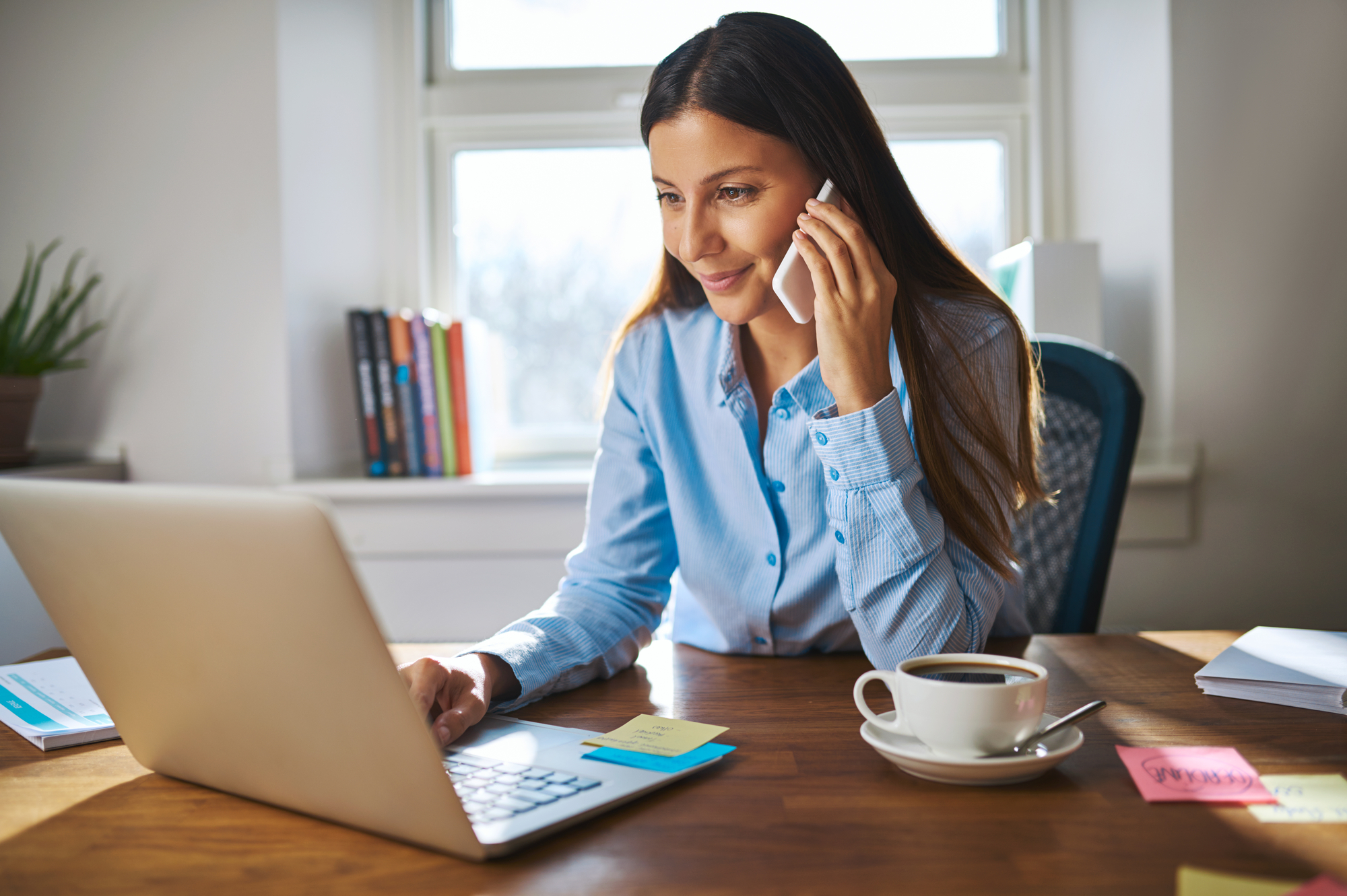 Lady at Table With Laptop, Speaking on Phone.