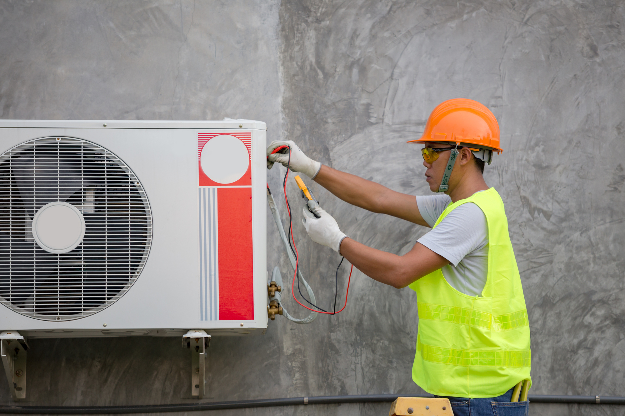 Worker in Safety Gear Repairing an Air Conditioner.